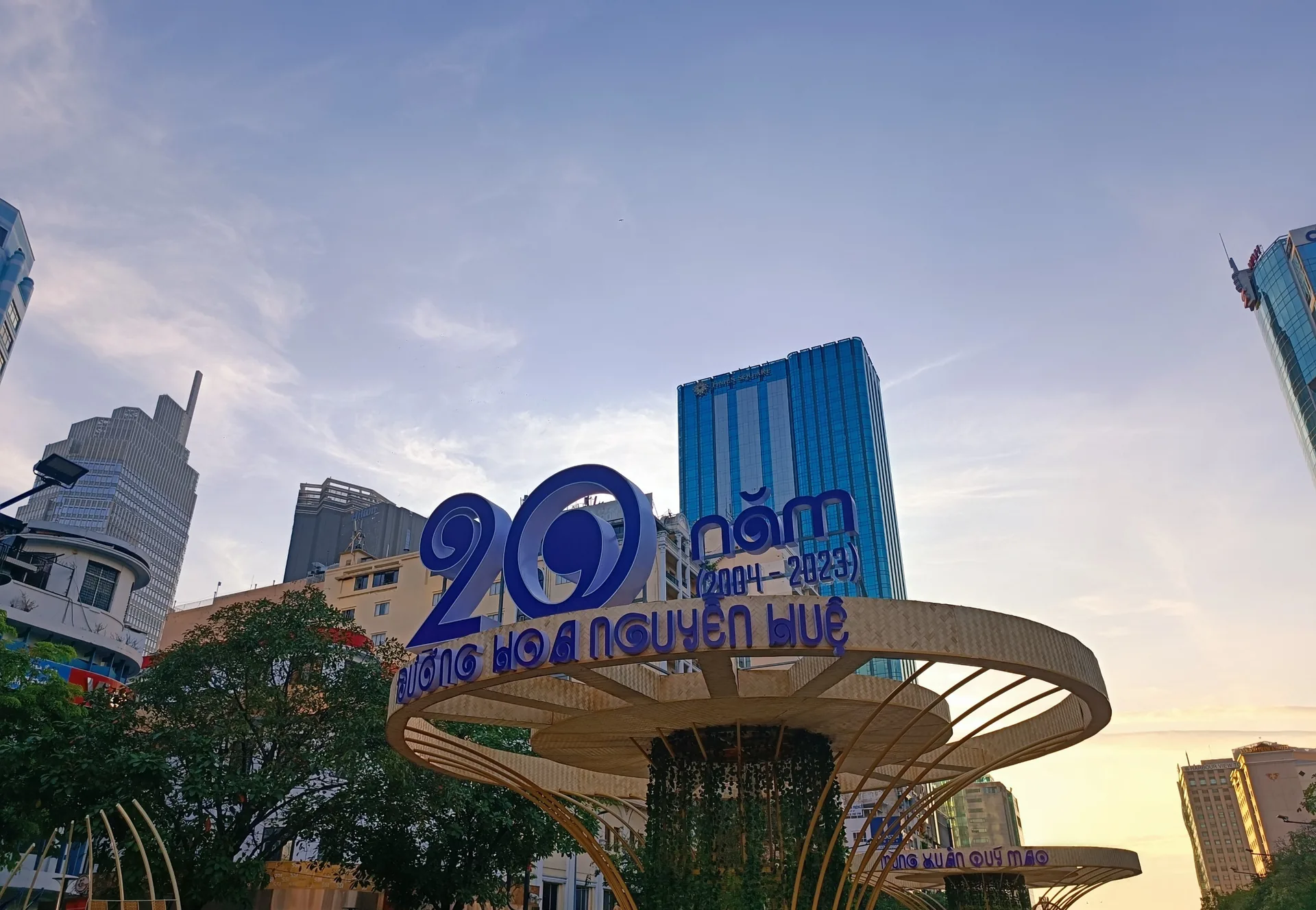An archive view of the Nguyen Hue flower-street entrance in Ho Chi Minh City with greenery and buildings at sunset