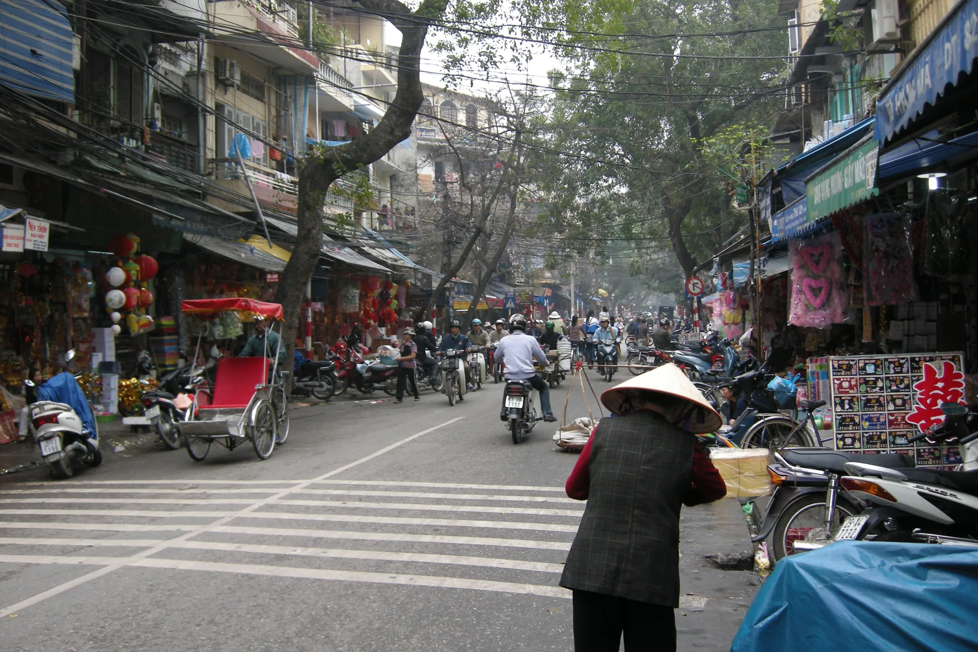 Busy Hanoi street with motorbikes, shops, and pedestrians
